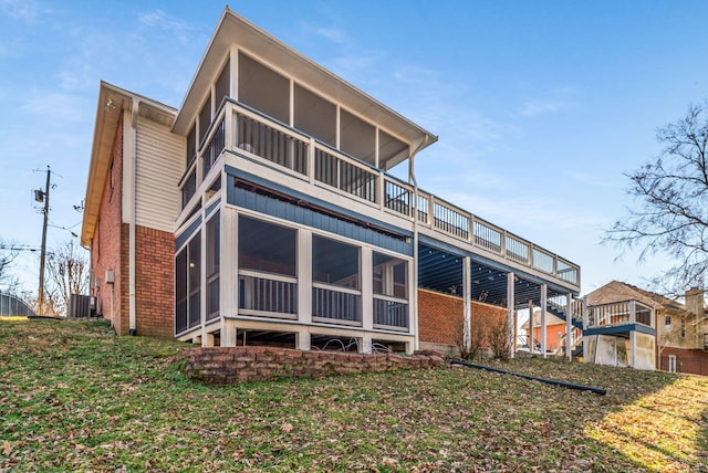 back of house featuring a sunroom, central AC, and brick siding