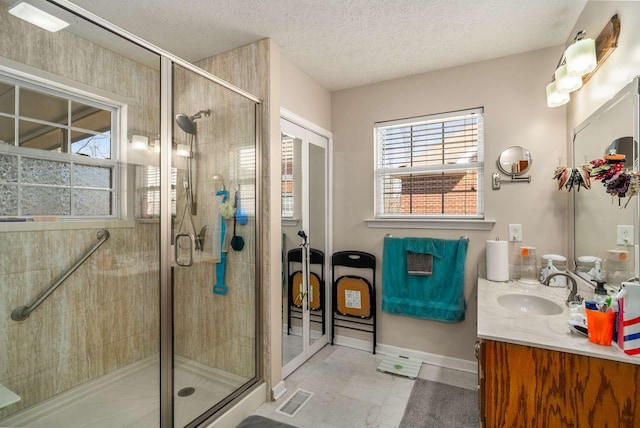 full bathroom featuring a textured ceiling, vanity, visible vents, baseboards, and a stall shower