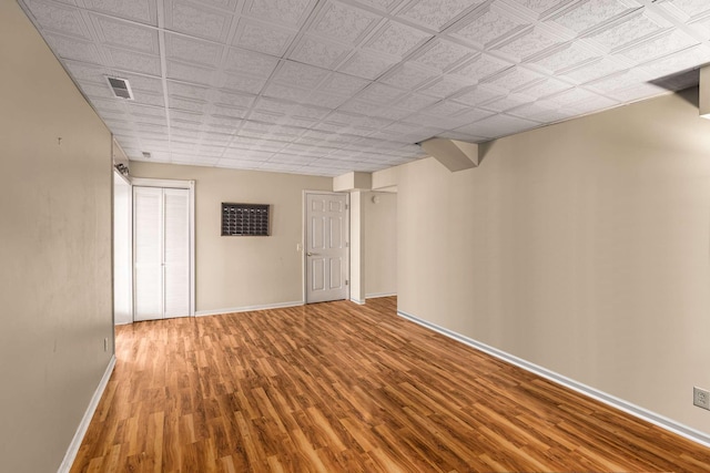 below grade area with visible vents, baseboards, and wood finished floors