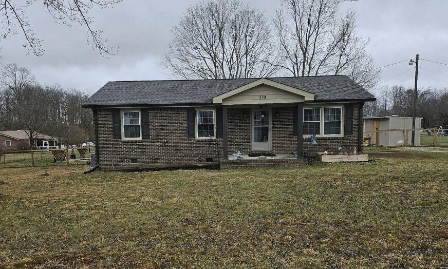 view of front facade featuring brick siding, crawl space, a shingled roof, and a front lawn