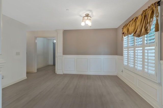 unfurnished room featuring a wainscoted wall and light wood-style floors