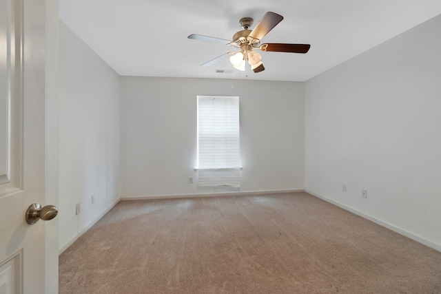 empty room featuring baseboards, ceiling fan, visible vents, and light colored carpet