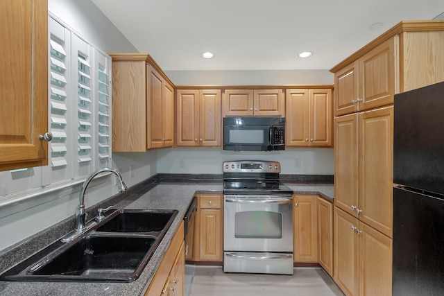 kitchen with recessed lighting, dark stone counters, a sink, and black appliances