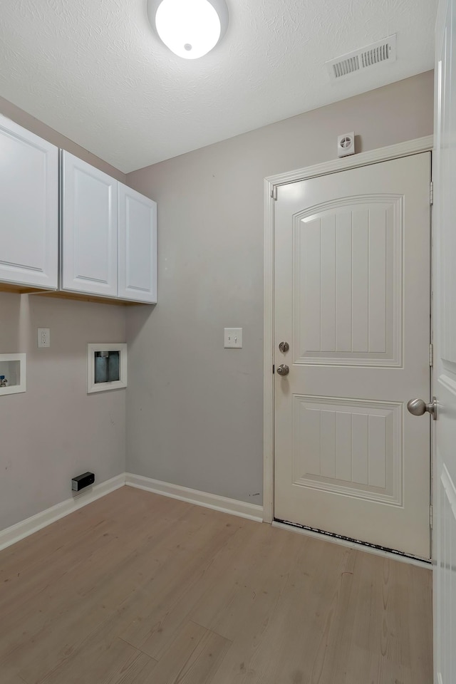 washroom featuring hookup for a washing machine, light wood-type flooring, cabinet space, and visible vents