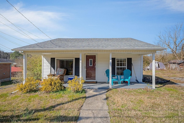 bungalow-style house featuring a front yard, covered porch, and roof with shingles