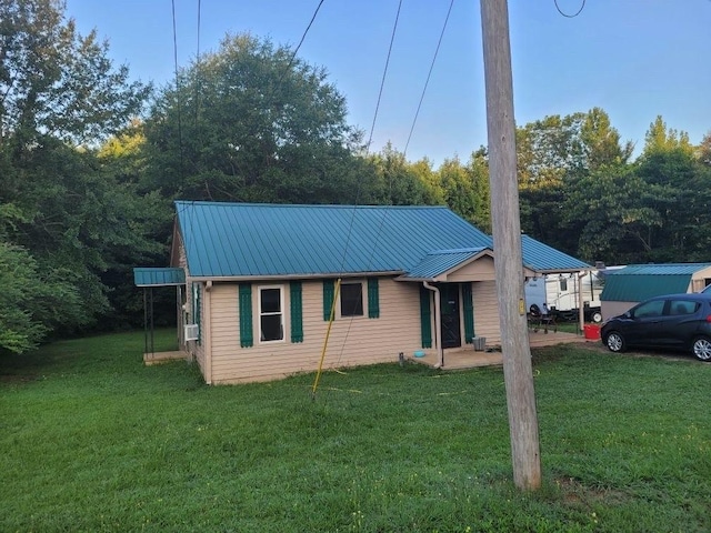 view of front of home featuring metal roof, a front yard, and cooling unit