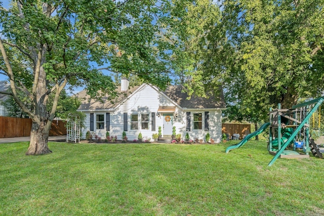 view of front facade featuring a front lawn, a chimney, a playground, and fence