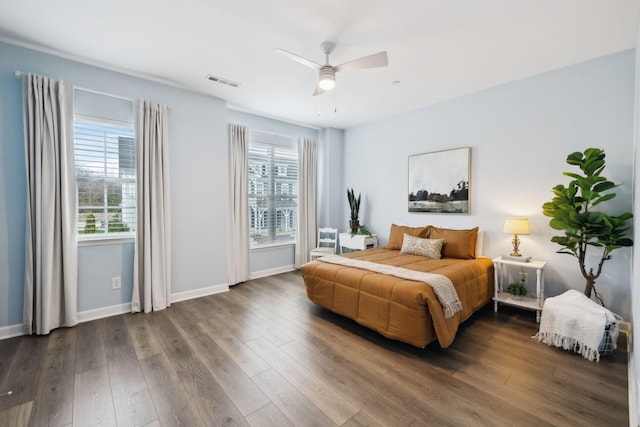 bedroom with dark wood-type flooring, multiple windows, visible vents, and baseboards