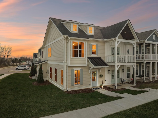 view of front facade featuring roof with shingles, board and batten siding, a patio, and a lawn