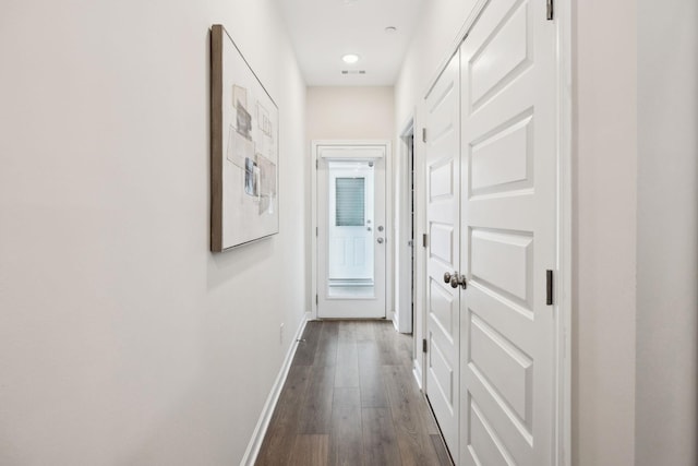 hall featuring visible vents, baseboards, and dark wood-type flooring