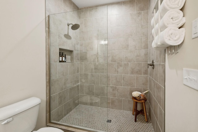 full bathroom featuring tiled shower and toilet