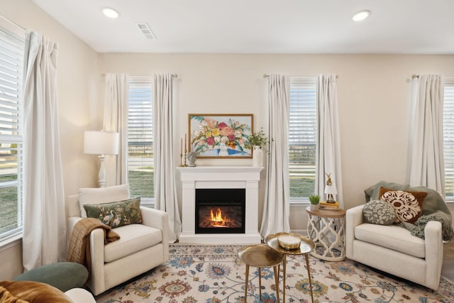 sitting room featuring a glass covered fireplace, visible vents, and recessed lighting