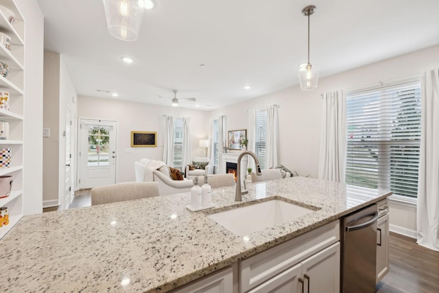 kitchen with a sink, open floor plan, a lit fireplace, hanging light fixtures, and open shelves