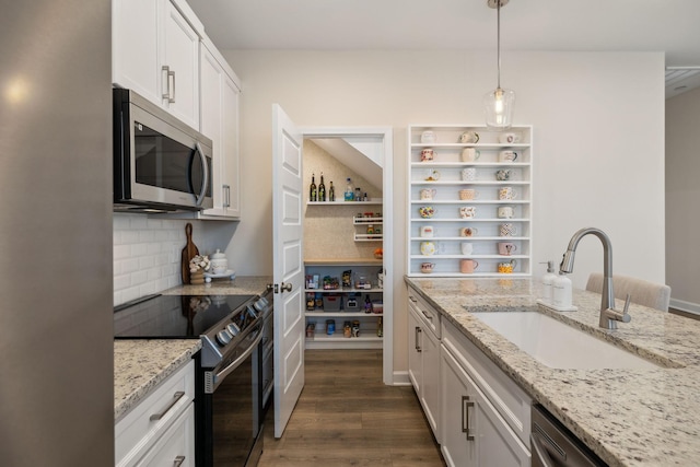 kitchen with dark wood-style floors, decorative backsplash, appliances with stainless steel finishes, white cabinets, and a sink