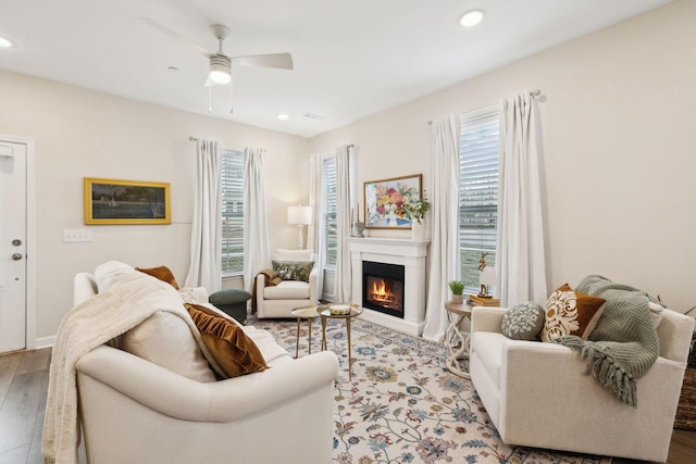 living room with baseboards, a glass covered fireplace, ceiling fan, wood finished floors, and recessed lighting