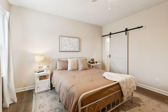 bedroom with a barn door, baseboards, and wood finished floors