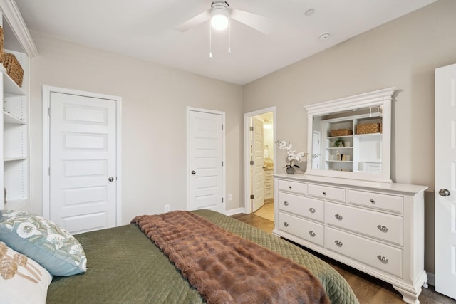 bedroom with ceiling fan, ensuite bathroom, and wood finished floors