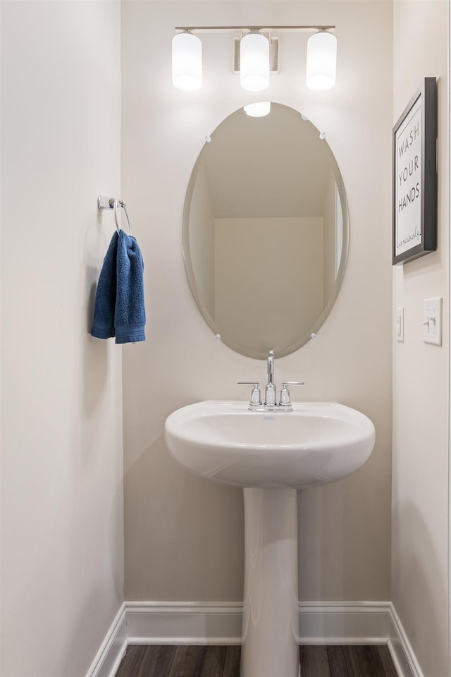 bathroom with a sink, baseboards, and wood finished floors