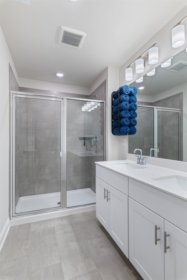 full bath with a sink, visible vents, and a shower stall