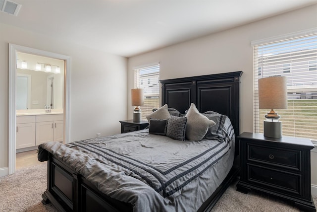 bedroom with ensuite bath, visible vents, and a sink