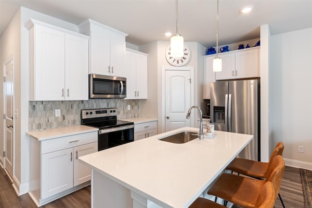 kitchen with a breakfast bar, a center island with sink, backsplash, appliances with stainless steel finishes, and a sink