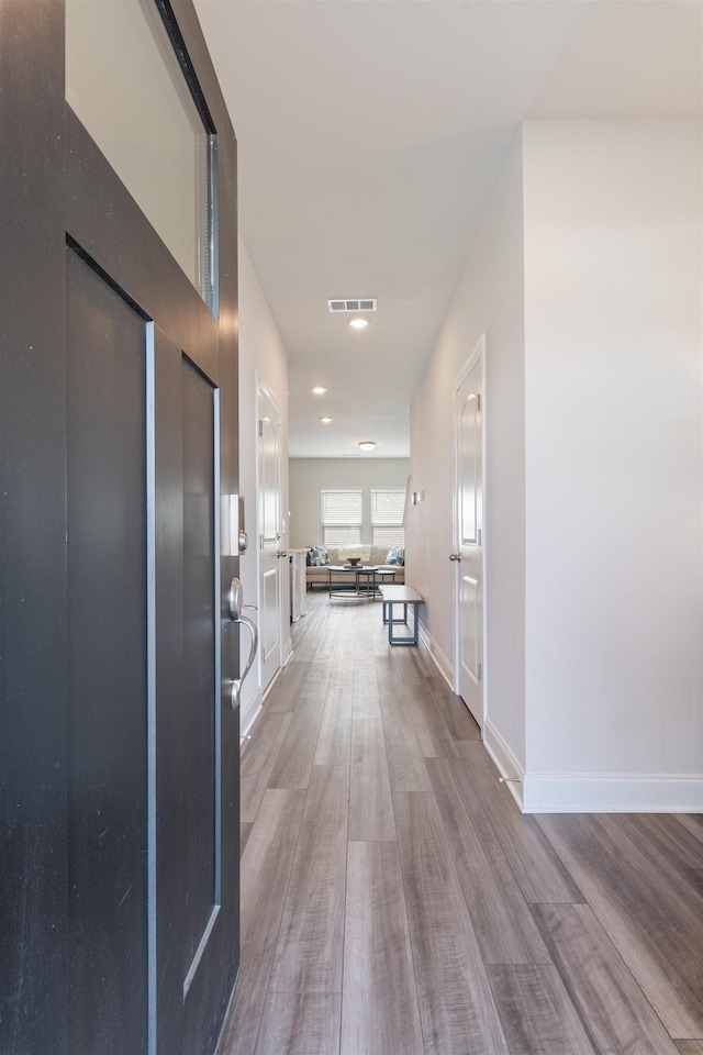 corridor featuring visible vents, baseboards, wood finished floors, and recessed lighting