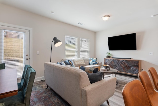 living area featuring wood finished floors, visible vents, and baseboards