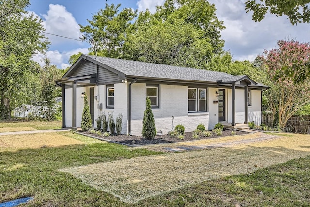 ranch-style house with a shingled roof, a front yard, brick siding, and fence