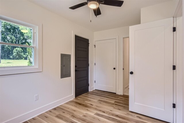 unfurnished bedroom with light wood-style floors, electric panel, ceiling fan, and baseboards