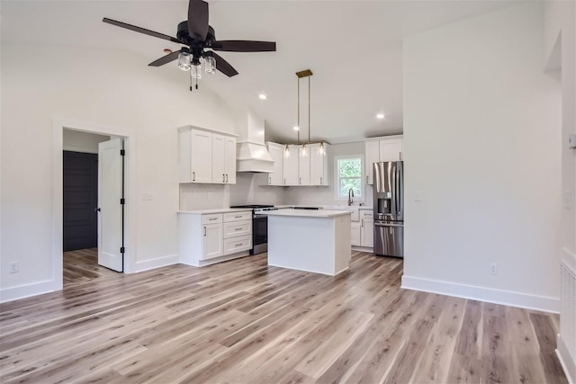 kitchen with stainless steel appliances, light countertops, custom range hood, light wood-style flooring, and white cabinetry