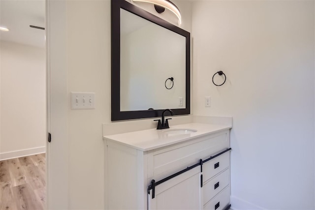 bathroom featuring wood finished floors, vanity, and baseboards