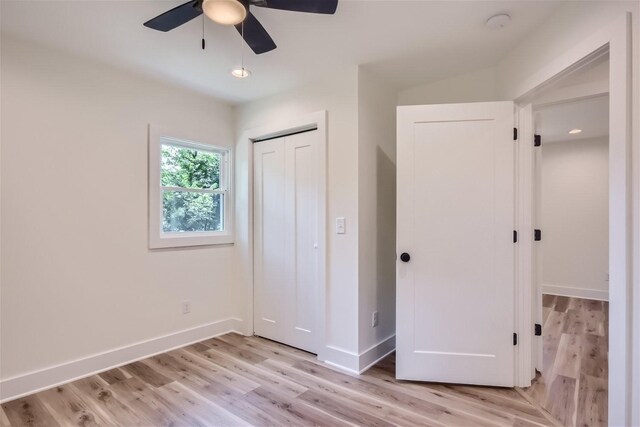 unfurnished bedroom featuring ceiling fan, light wood finished floors, a closet, and baseboards