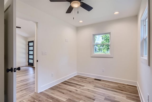 spare room with light wood finished floors, visible vents, and baseboards