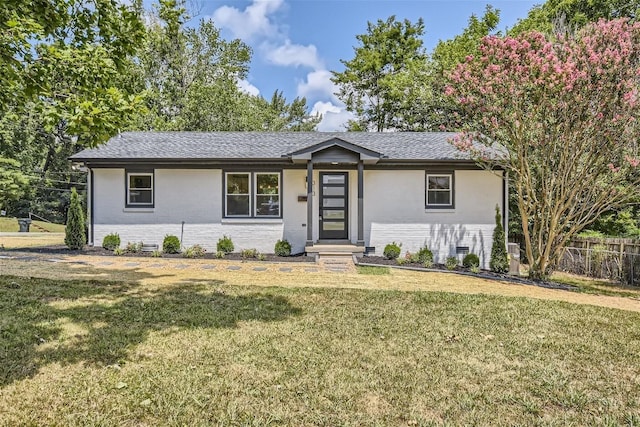 ranch-style house featuring a shingled roof, fence, a front lawn, and brick siding