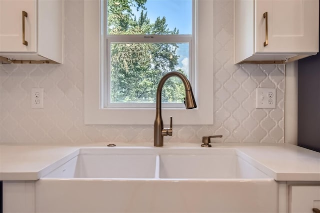 kitchen featuring light countertops, a sink, white cabinetry, and wallpapered walls