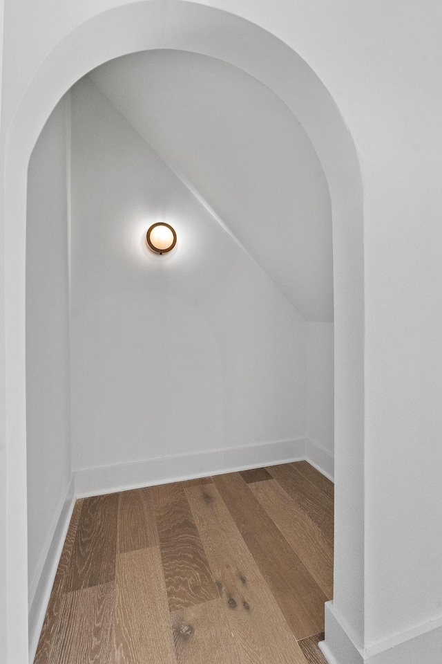 interior space featuring baseboards, arched walkways, and wood finished floors