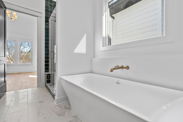 bathroom with marble finish floor, baseboards, a freestanding bath, and a stall shower