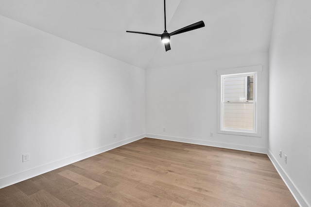 spare room with light wood finished floors, ceiling fan, baseboards, and vaulted ceiling