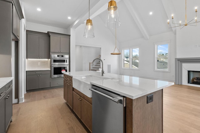 kitchen featuring gray cabinets, appliances with stainless steel finishes, a high end fireplace, a sink, and light wood-type flooring