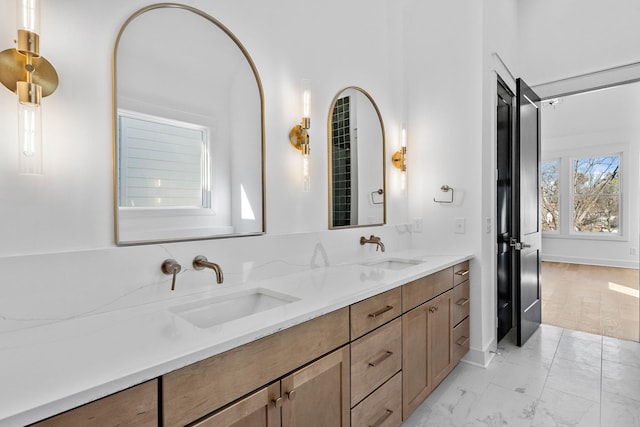 bathroom with double vanity, marble finish floor, and a sink