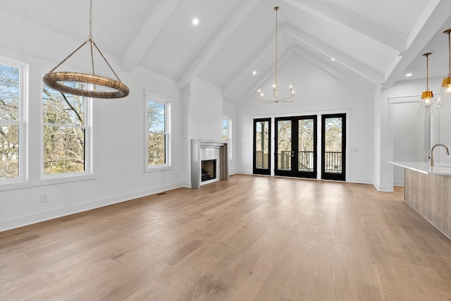 unfurnished living room with light wood-style floors, beam ceiling, and plenty of natural light