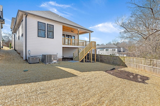 rear view of house with a shingled roof, fence, stairway, and central AC