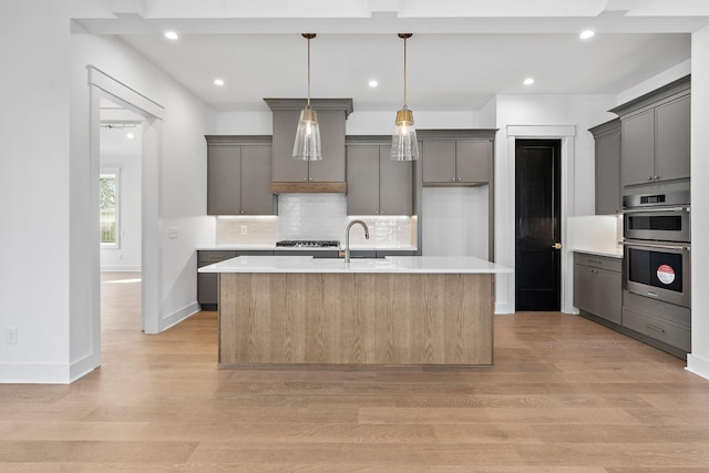 kitchen featuring tasteful backsplash, light countertops, a sink, and light wood-style flooring