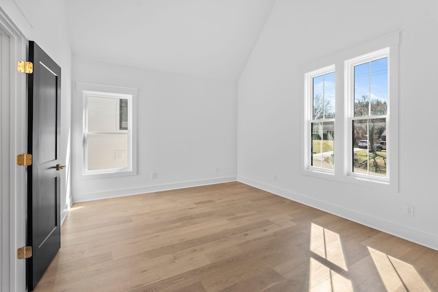 unfurnished room featuring light wood-style flooring, baseboards, and vaulted ceiling