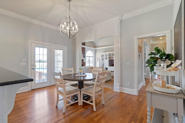 dining room with baseboards, light wood-style floors, an inviting chandelier, and crown molding