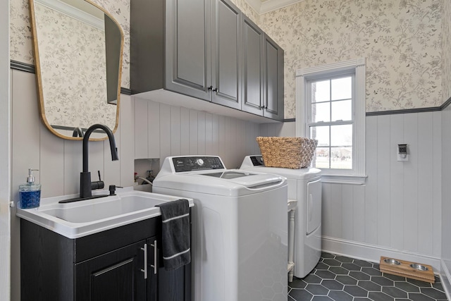 laundry room with cabinet space, wallpapered walls, wainscoting, washer and dryer, and a sink