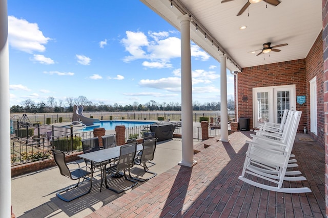 view of patio / terrace with a fenced in pool, outdoor dining area, french doors, ceiling fan, and fence