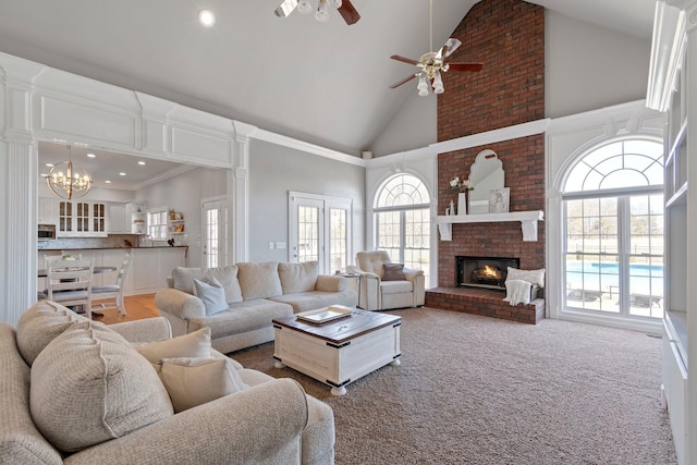 living area with high vaulted ceiling, recessed lighting, ceiling fan with notable chandelier, carpet floors, and a fireplace