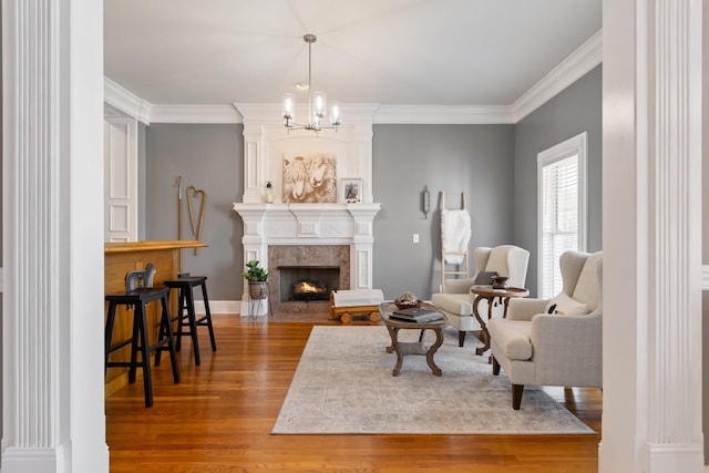 sitting room with a notable chandelier, a premium fireplace, wood finished floors, baseboards, and crown molding