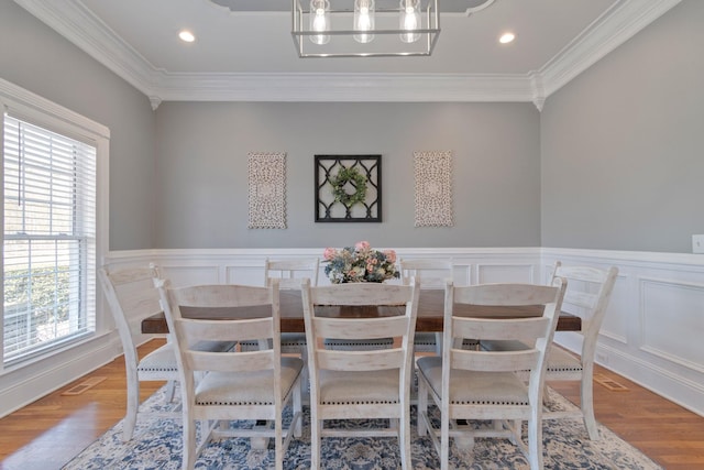 dining space featuring ornamental molding, a wainscoted wall, and wood finished floors